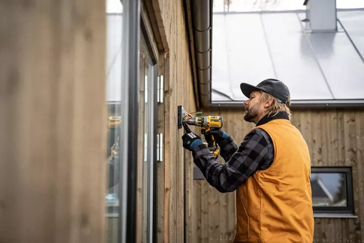 A tradesman drilling into an exterior wall