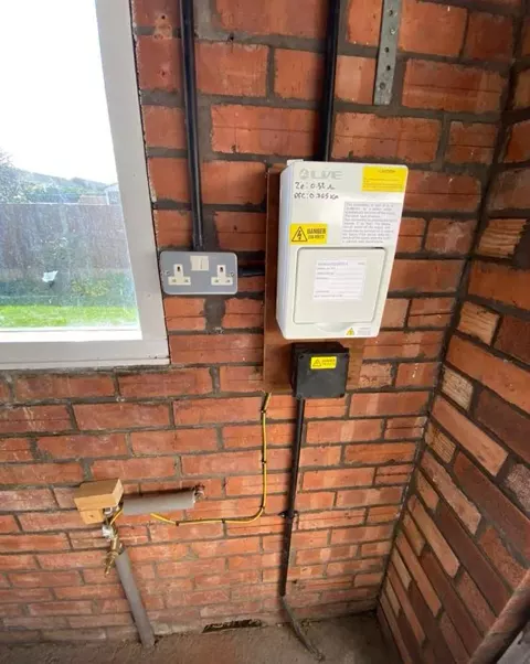 An electricity meter and isolator switch on a brick wall