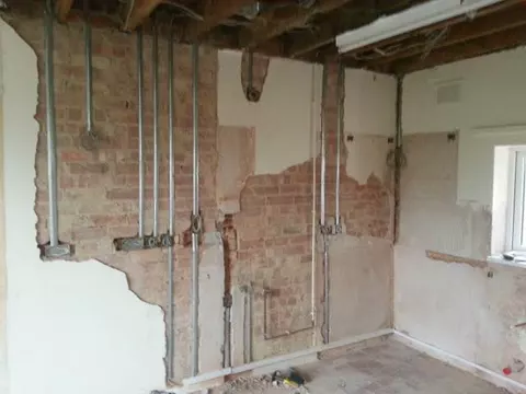 A room stripped back to brick with new cable routes chased in during a house rewire